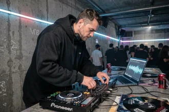 DJ passionné de musique techno derrière sa table de mixage dans un club underground avec murs en béton