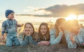 3 women sitting on grass field during sunset