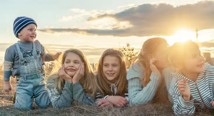 3 women sitting on grass field during sunset